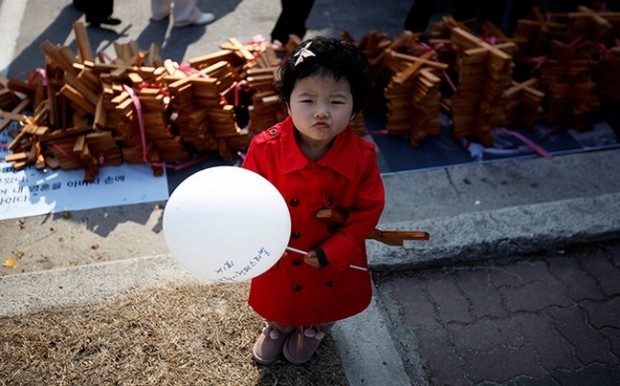 A girl stands in front of crosses before a procession to celebrate Easter