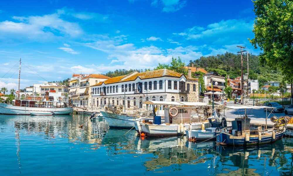 Το γραφικό λιμάνι του Λιμένα Θάσου με αλιευτικά σκάφη και παραδοσιακή αρχιτεκτονική.